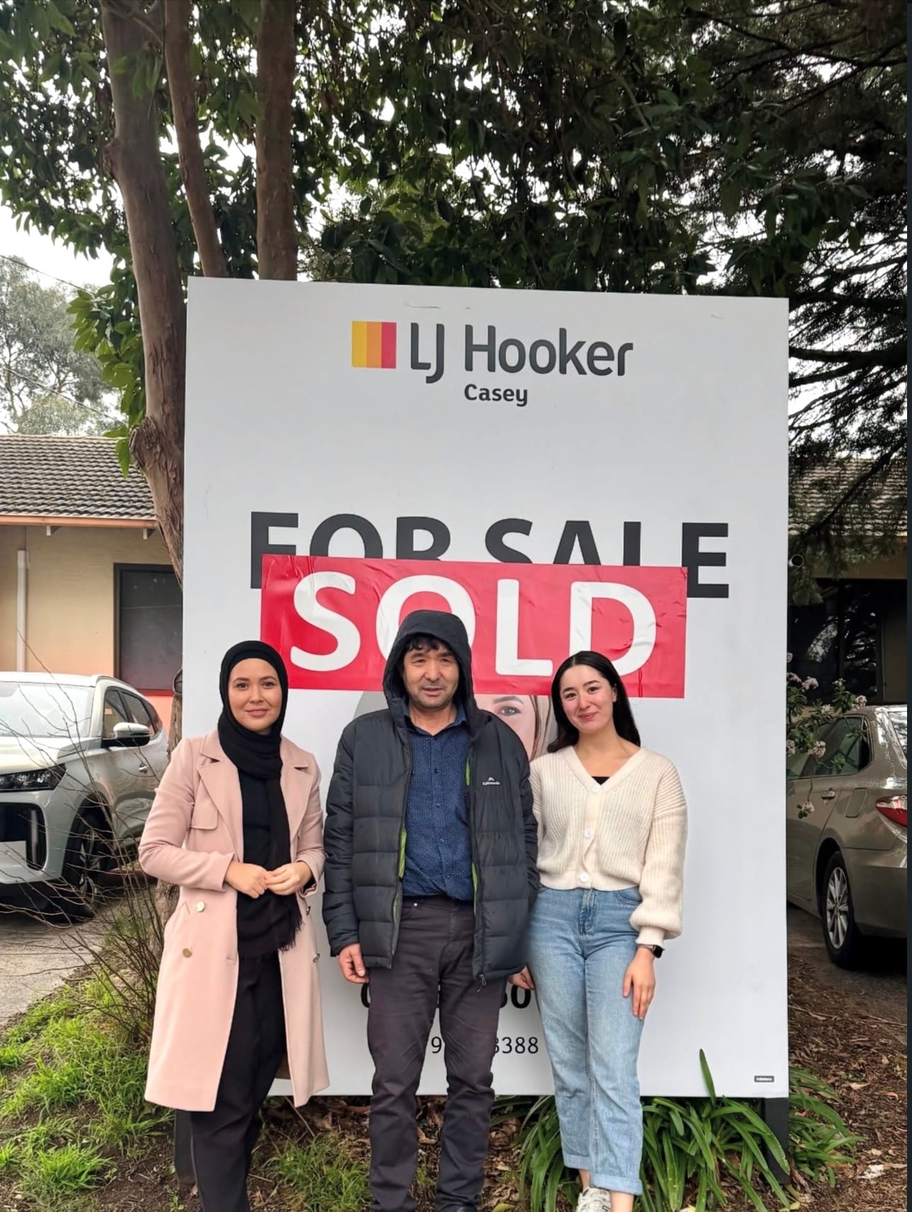 Fatima Yazdani with clients in front of an LJ Hooker Casey SOLD board.