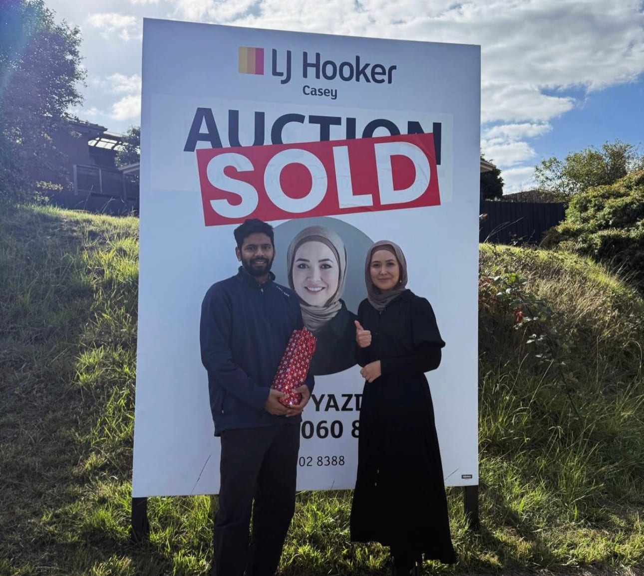 An LJ Hooker Casey AUCTION SOLD board with Fatima Yazdani and a happy buyer.