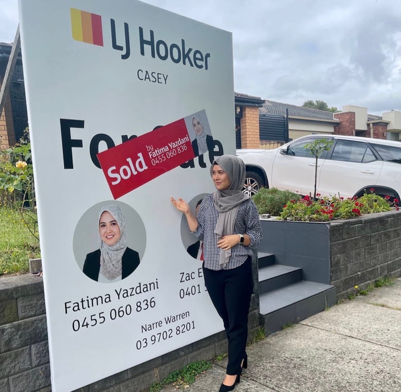 Fatima Yazdani pointing to her SOLD sticker on an LJ Hooker Casey board in Narre Warren.